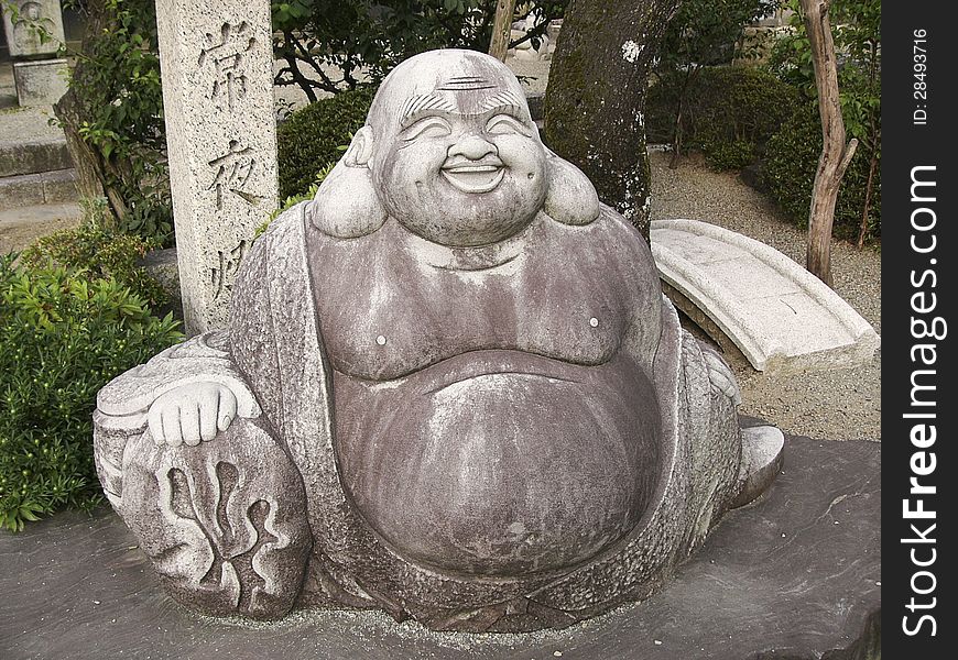 Sculpture of Japanese god Hotei at Temple in southern Japan. Hotei is one of Japan's Seven Lucky Gods also known as God of contentment and happiness.