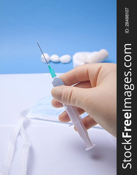 Doctor's Hand Holding Syringe On A Blue Background