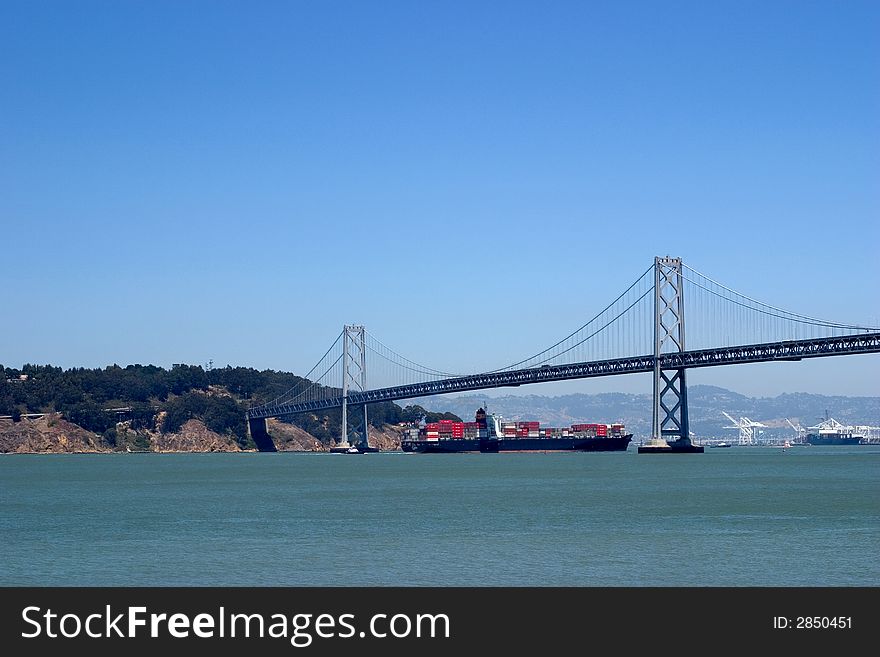 A huge containership passes under the Oakland Bay bridge. A huge containership passes under the Oakland Bay bridge