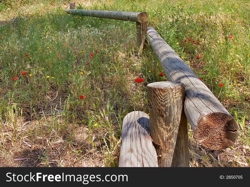 A small fence from logs on a blossoming meadow a log. A small fence from logs on a blossoming meadow a log