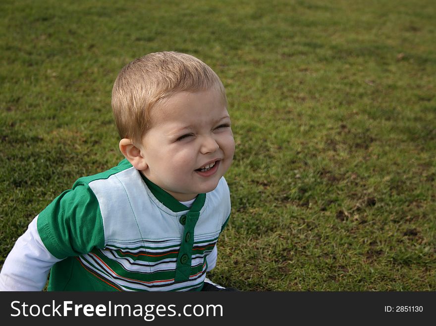 Toddler sitting on the grass, making faces for the camera. Toddler sitting on the grass, making faces for the camera