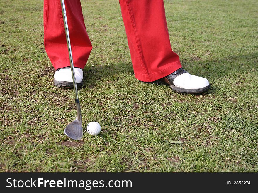 Legs of a male golfer wearing red trousers. Legs of a male golfer wearing red trousers