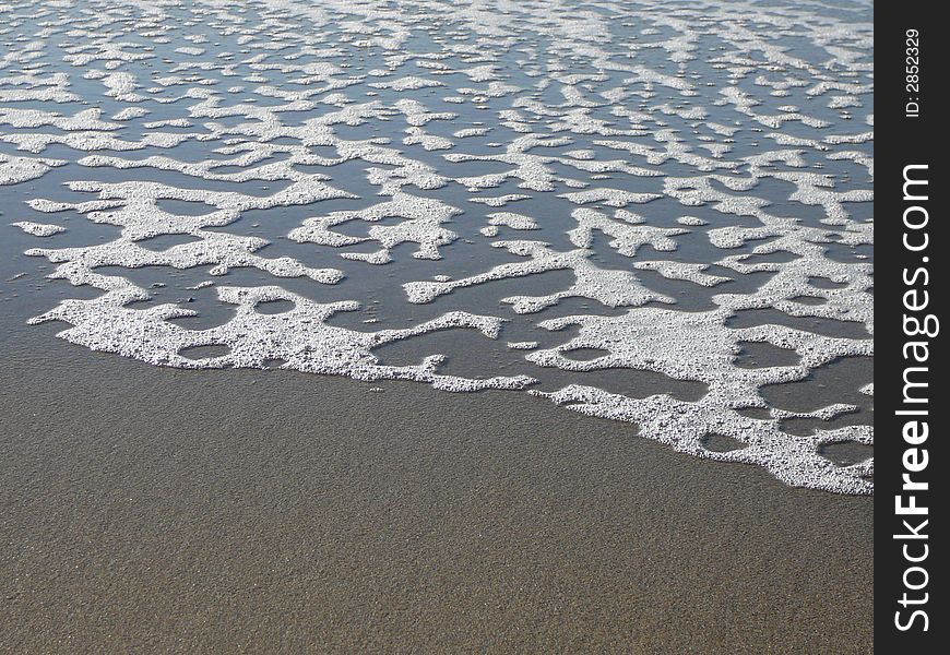 Foam left on a beach by a receding wave. Foam left on a beach by a receding wave