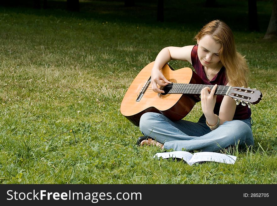 Portrait of the girl with a guitar having a rest in the summer in park. Portrait of the girl with a guitar having a rest in the summer in park