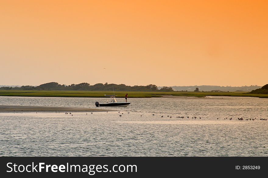 A lone small boat by a sand bar on the sound at low tide in the evening. A lone small boat by a sand bar on the sound at low tide in the evening