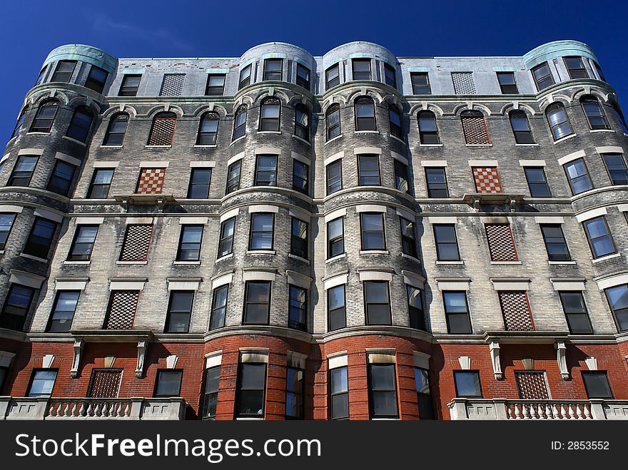 Subtle yet ornate apartment house in downtown cambridge massachusetts with checker board designs and round corners against a deep blue sky. Subtle yet ornate apartment house in downtown cambridge massachusetts with checker board designs and round corners against a deep blue sky