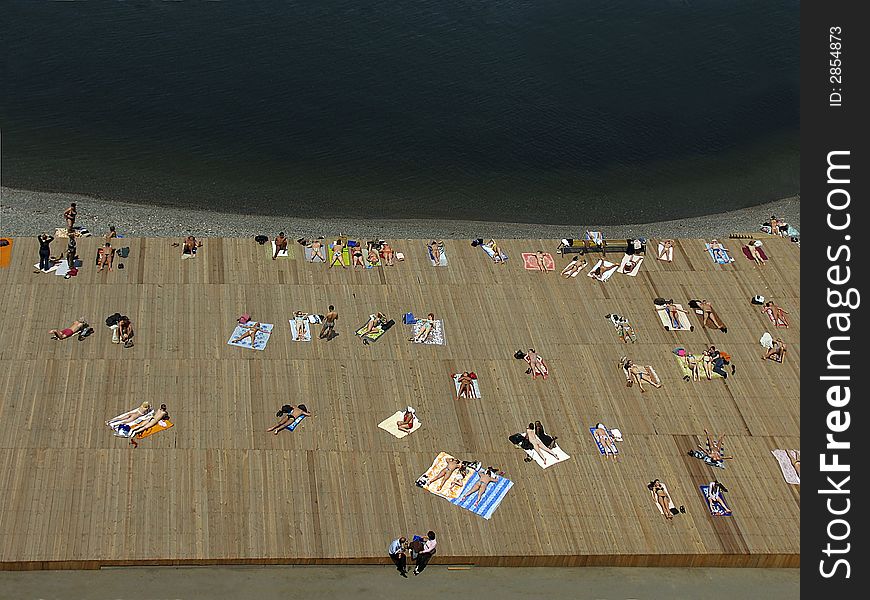 Sunburned peoples on wooden beach near the sea