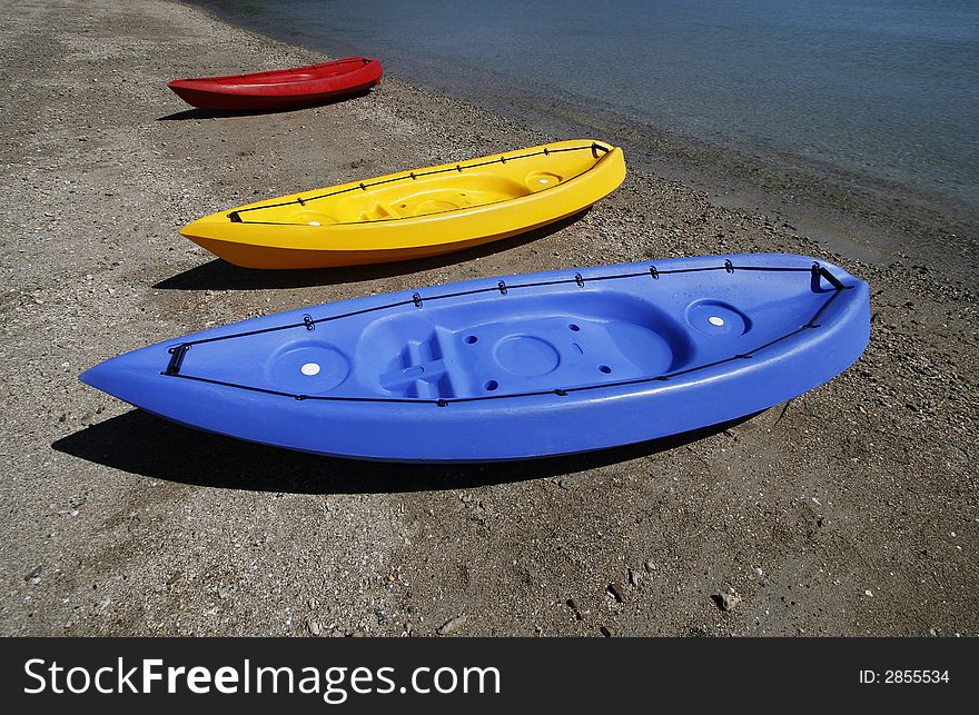 colorful kayaks on beach by turquoise waters