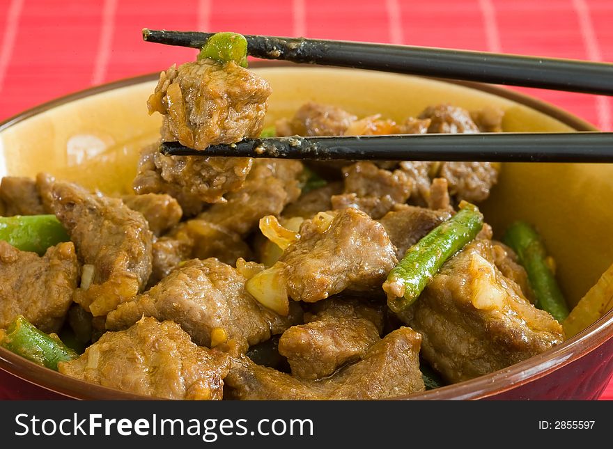 Asian food of beef and vegetables on brown bowl and black chopstick. Asian food of beef and vegetables on brown bowl and black chopstick