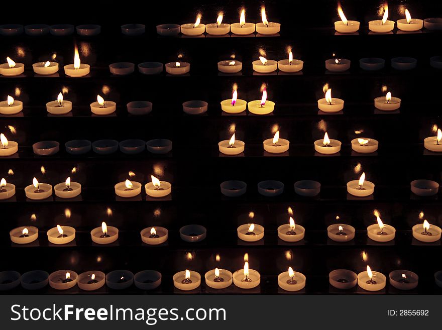 Candles alight within a church. Candles alight within a church