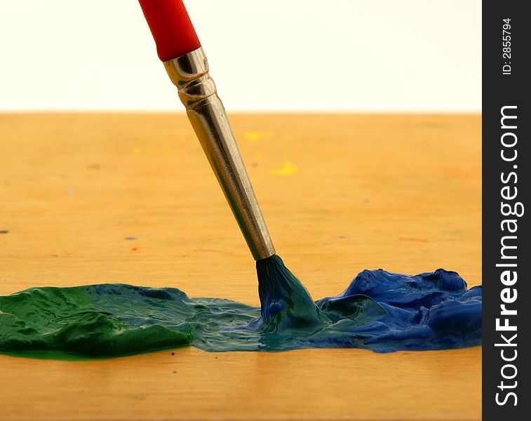 Mixing green and blue color with brush on wooden palette. Mixing green and blue color with brush on wooden palette.