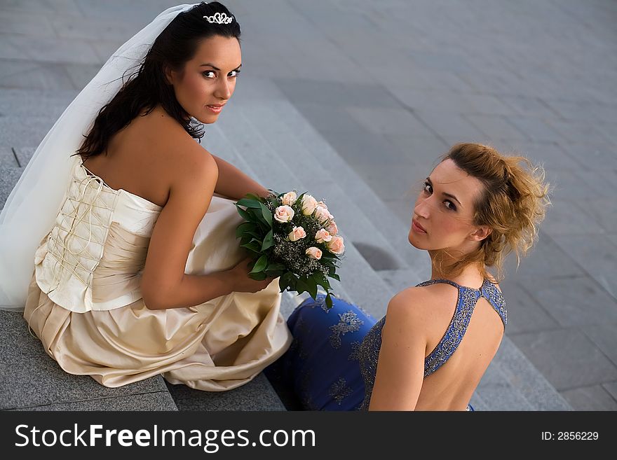 Bride and bridesmaid are talking in front of the church. Bride and bridesmaid are talking in front of the church