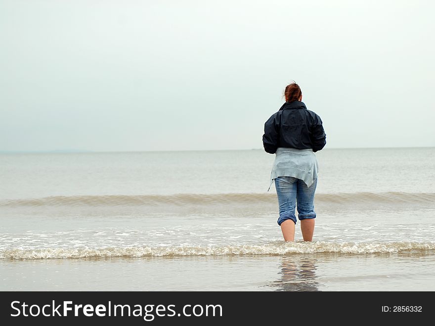Woman stand in cold sea on empty beach. Woman stand in cold sea on empty beach.