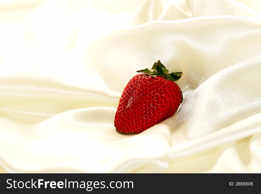Single strawberry on a cloud of soft white satin