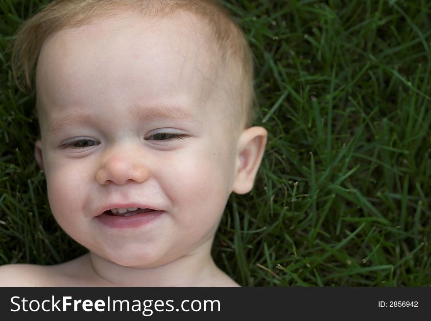 Image of cute laughing toddler laying in the grass. Image of cute laughing toddler laying in the grass