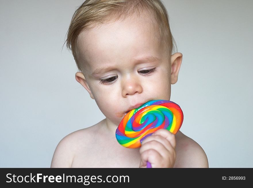 Image of cute toddler licking a colorful lollipop. Image of cute toddler licking a colorful lollipop