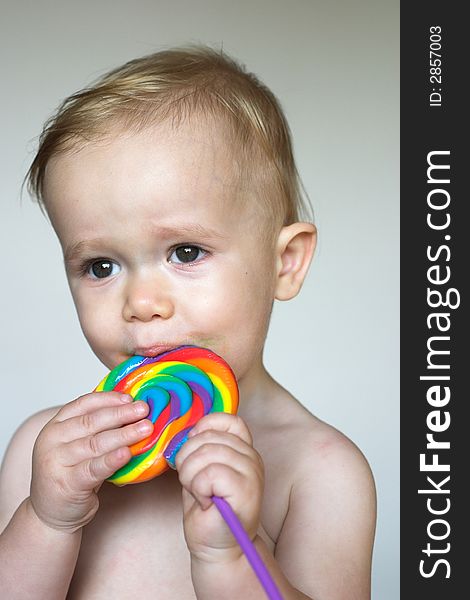 Image of cute toddler licking a colorful lollipop. Image of cute toddler licking a colorful lollipop