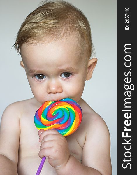 Image of cute toddler licking a colorful lollipop. Image of cute toddler licking a colorful lollipop