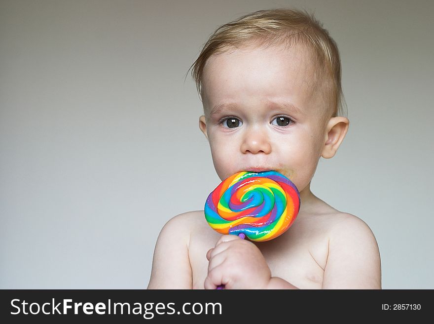 Image of cute toddler licking a colorful lollipop. Image of cute toddler licking a colorful lollipop