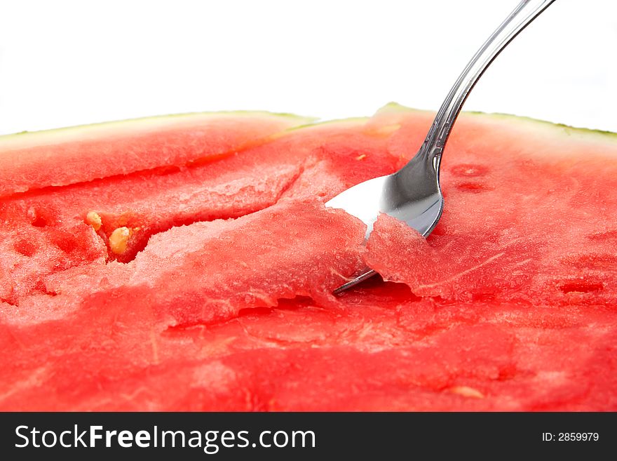 Close-up of a spoon dipping into a juicy watermelon. Focus on the spoon.