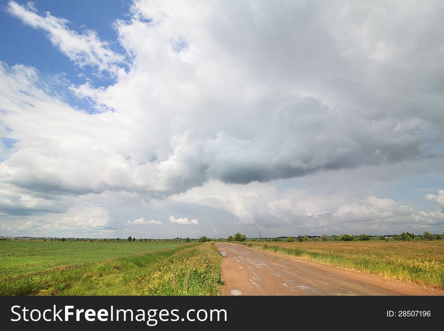 Cumulus Clouds Above The Road In The Steppe.