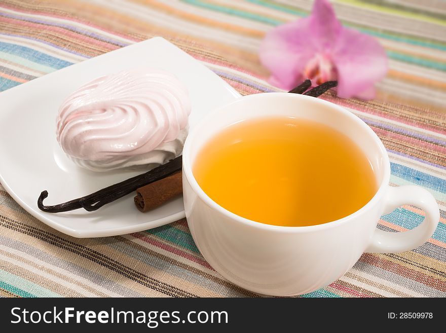 Cup of tea and pink marshmallow on a saucer with a vanilla