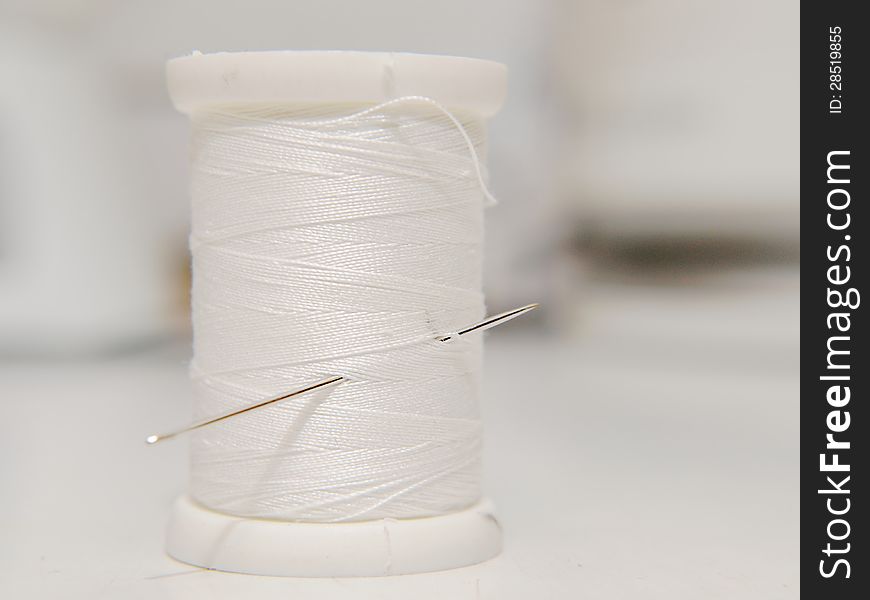 White thread on spool, standing position, with needle