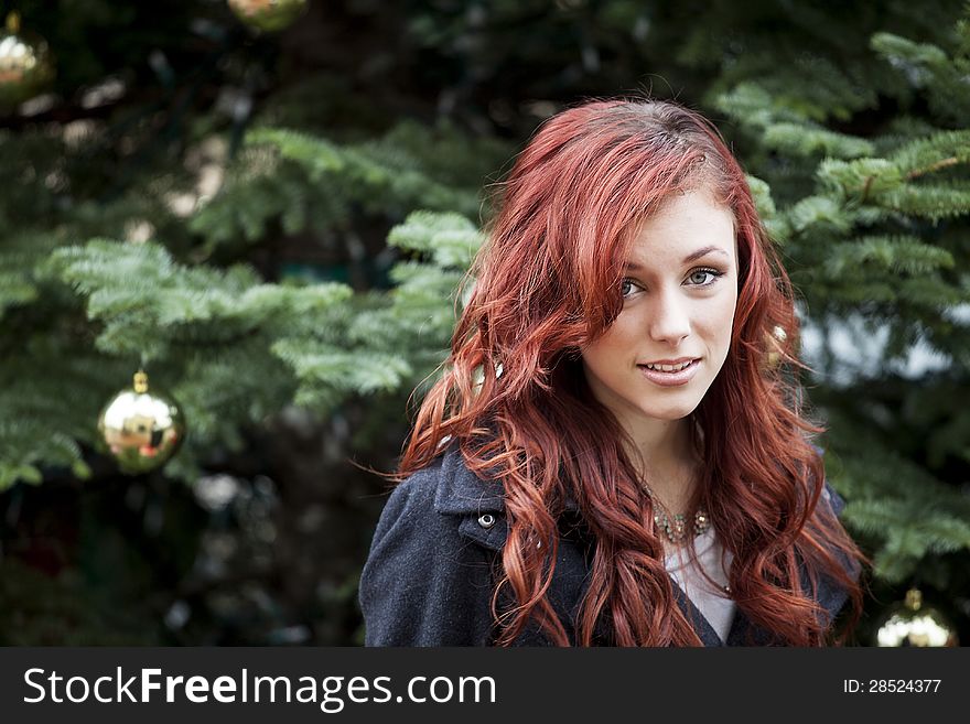 Young woman with beautiful red hair in front of a Christmas tree. Young woman with beautiful red hair in front of a Christmas tree.