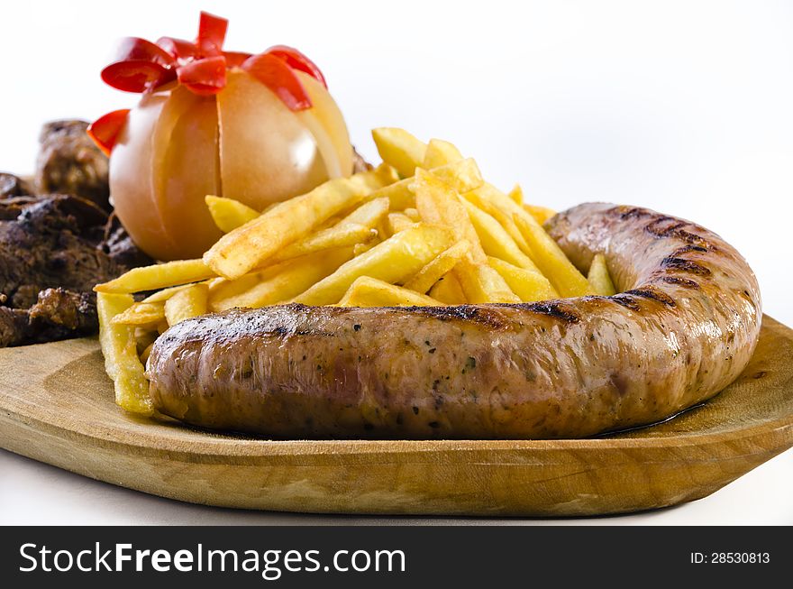 Rustic tray with various meats, french fries and assorted vegetables