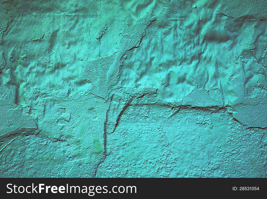 Abstract background texture of a damaged painted turquoise wall with cracked and missing plaster that has been painted over to try and conceal the damage