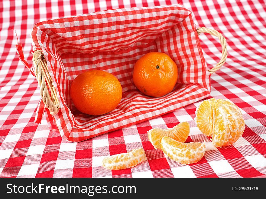 Clementine fruits, one opened, on red check fabric surface