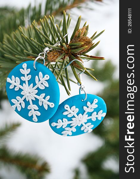 Two blue snowflake model earrings for present with a pin tree branch. Two blue snowflake model earrings for present with a pin tree branch