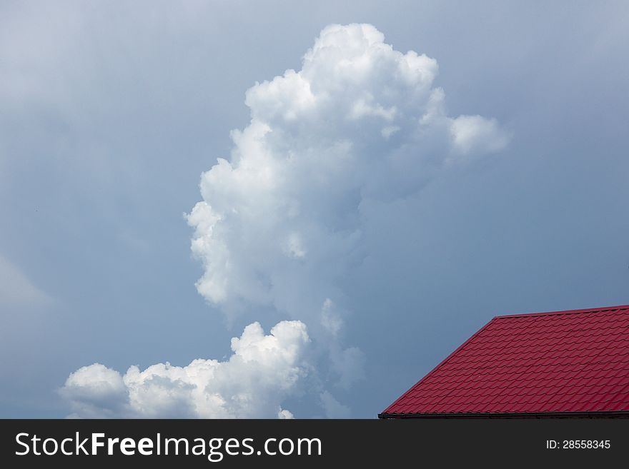 Red house roof on blue sky with clouds background. Red house roof on blue sky with clouds background