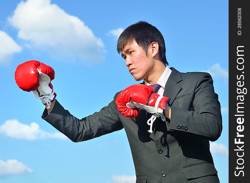 Businessman and hand boxing glove ready to fight over blue sky. Businessman and hand boxing glove ready to fight over blue sky