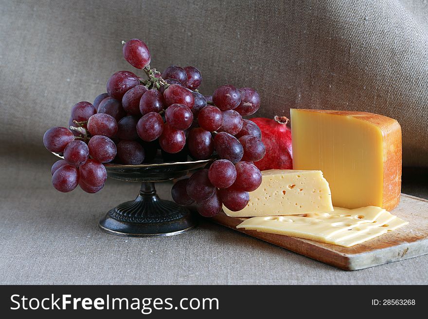 Still life with few sorts of cheese on wooden hardboard near fruits. Still life with few sorts of cheese on wooden hardboard near fruits