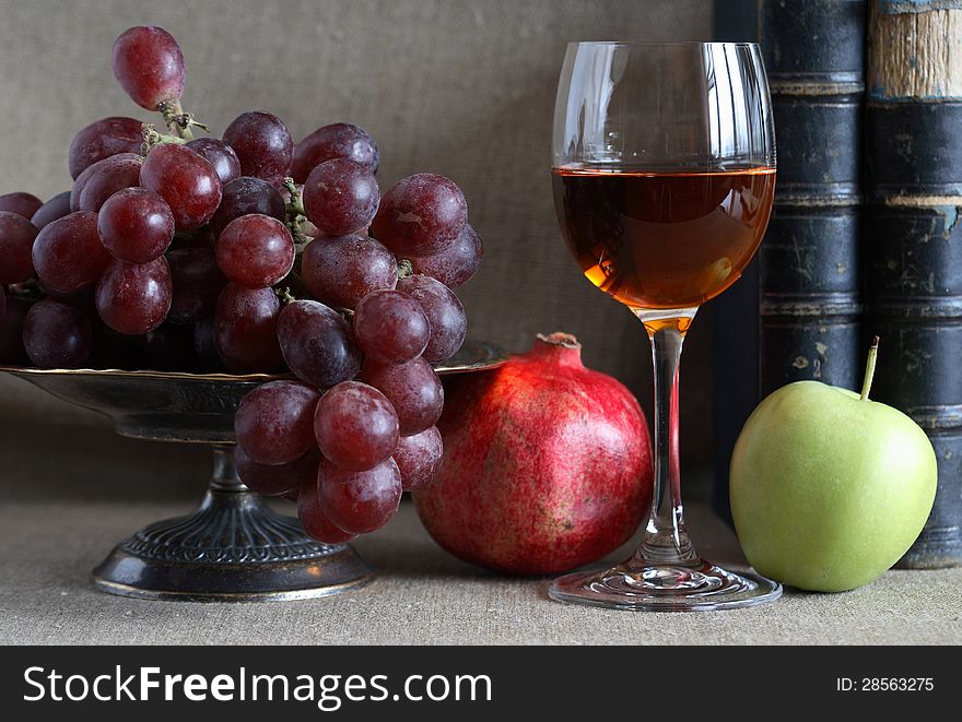 Vintage still life with fruits in bowl and wineglass near old books. Vintage still life with fruits in bowl and wineglass near old books