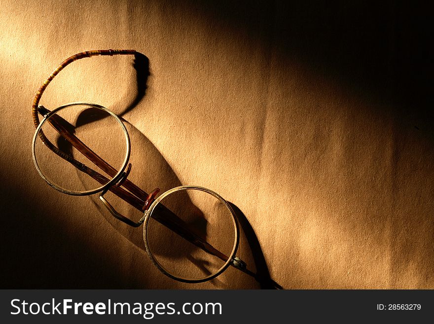 Old spectacles on paper surface under beam of light