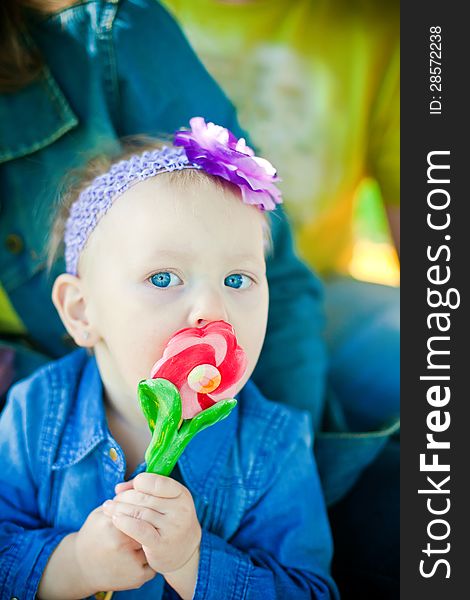 Little girl licking sweet flower-shaped lollipop. Little girl licking sweet flower-shaped lollipop
