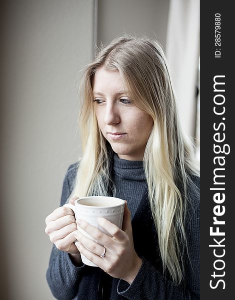 Pretty young blonde woman drinking her morning coffee. Pretty young blonde woman drinking her morning coffee.