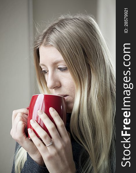 Pretty young blonde woman drinking her morning coffee. Pretty young blonde woman drinking her morning coffee.