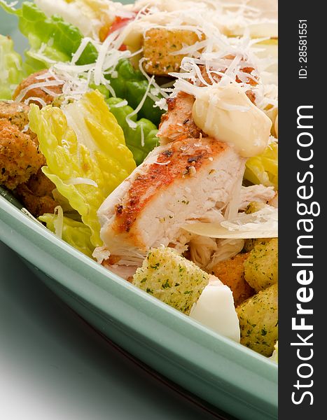 Caesar Salad with Grilled Chicken, Crouton, Romaine Lettuce, Sauce and Grated Parmesan Cheese closeup on Green Plate