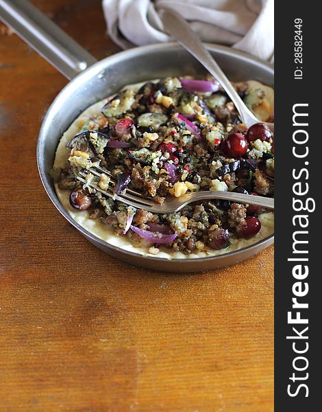 Wheat flat bread with mincemeat, roasted eggplant, red onion and red grape in a pan with napkin and fork and spoon in a pan