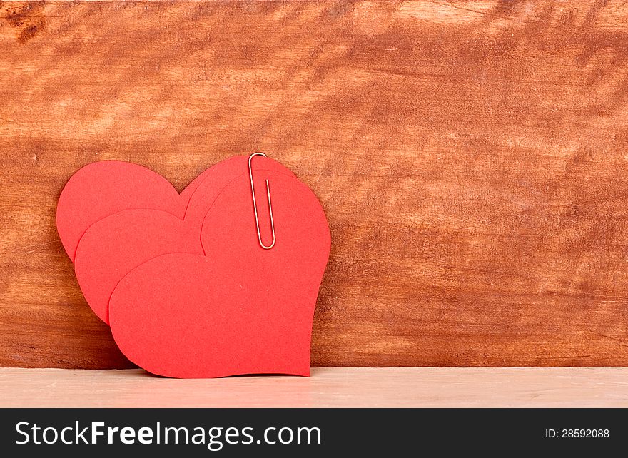 Three heart fastened by a paper-clip on the background of the old tree. Three heart fastened by a paper-clip on the background of the old tree