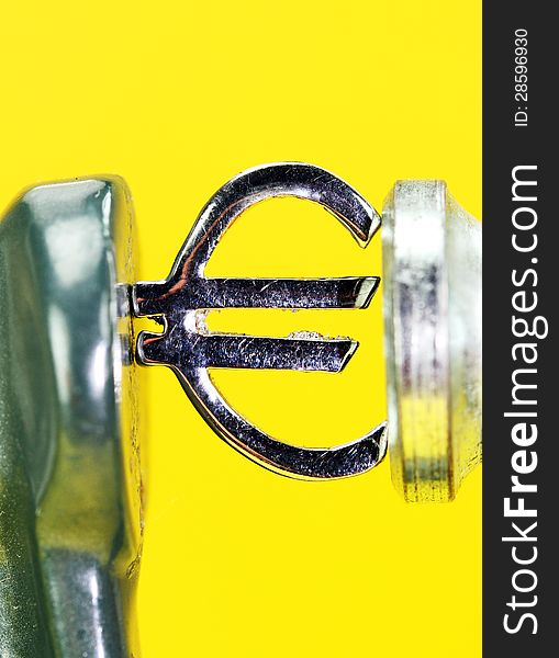 A silver Euro symbol placed in a clamp with yellow sunset background, indicating the pressure on the currency and that the sun is setting on the currency!. A silver Euro symbol placed in a clamp with yellow sunset background, indicating the pressure on the currency and that the sun is setting on the currency!