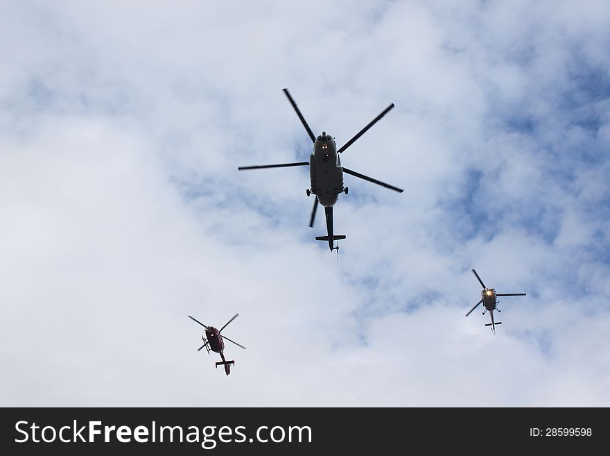 Helicopters flying in cloudy sky.