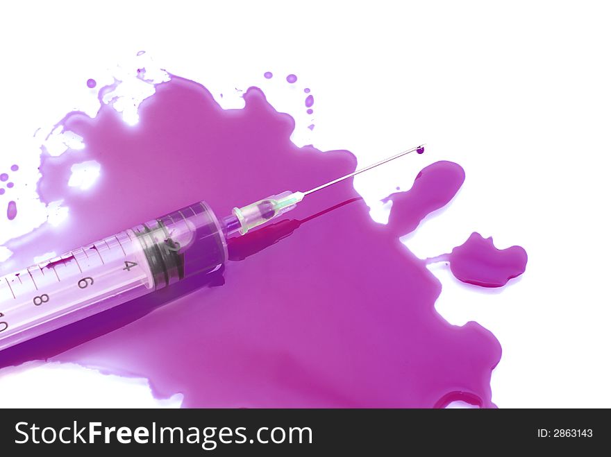 Syringe in a pool of a violet liquid on a white background. Syringe in a pool of a violet liquid on a white background