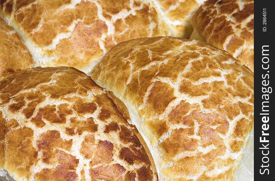 Detail of a tray of crusty bread rolls fresh from the oven.