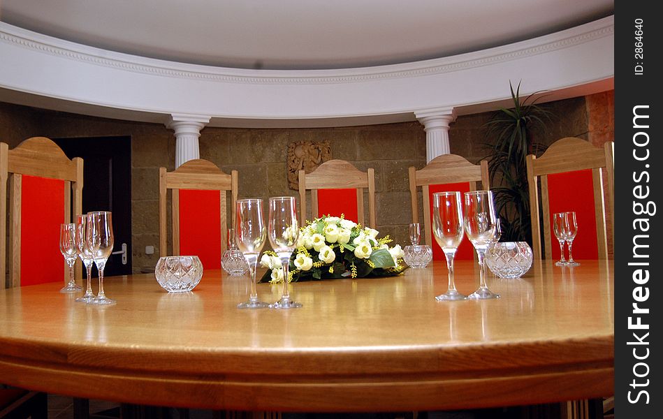 Glasses and vase with flowers on a table in a hall for reception of visitors