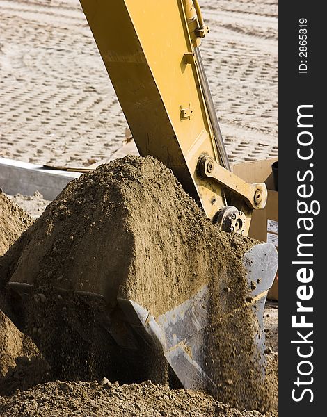 Excavator scooping dirt with its bucket. Vertical format. Excavator scooping dirt with its bucket. Vertical format.