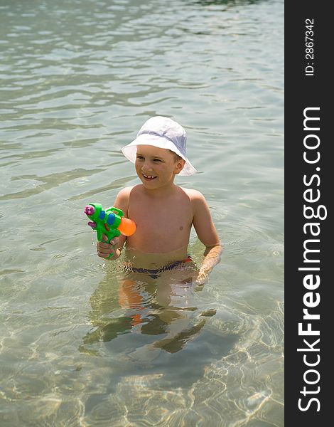 A boy with water pistol in the water